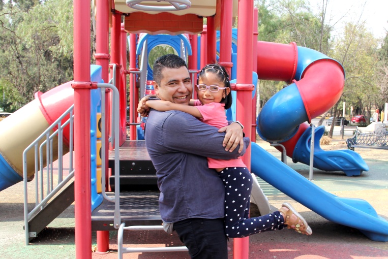  dad plays with his brunette latina daughter in playground park spins and hugs spend fun time