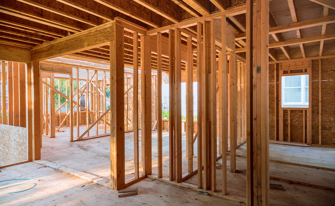 Interior view of a room under construction in McAllen, TX, highlighting wood framing and multiple windows.