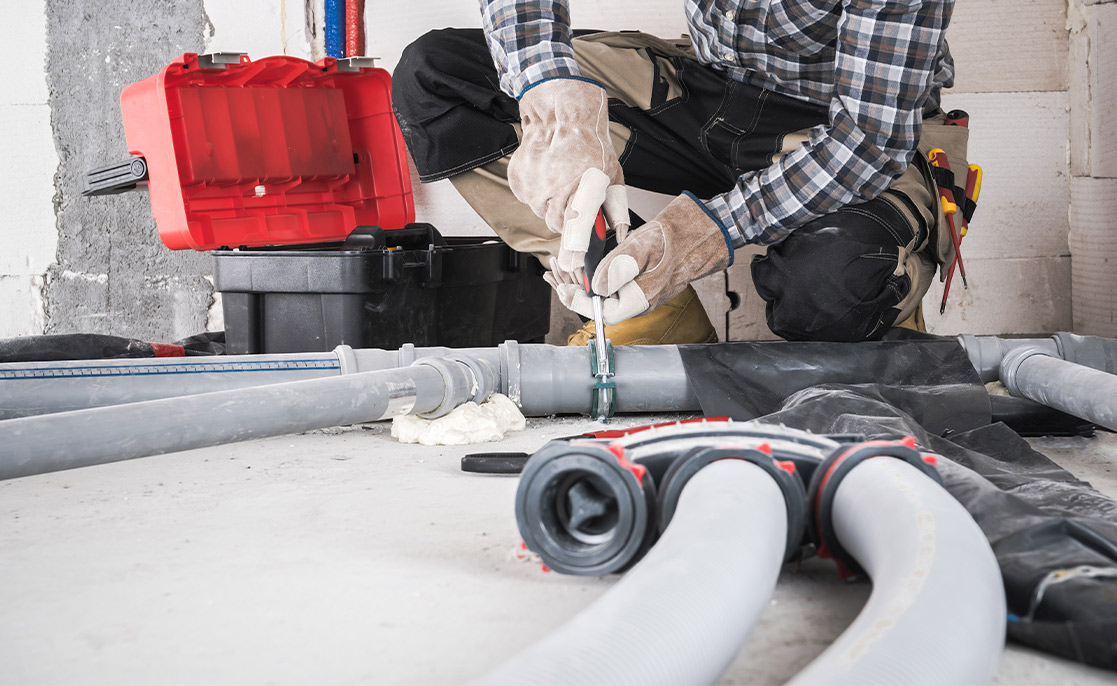 In a room, a man is repairing a pipe as part of new home construction in McAllen, Texas.