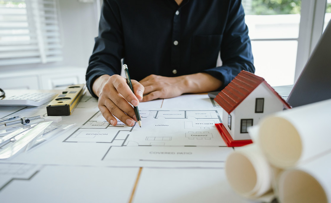 A man studies a house blueprint, contemplating how to choose the ideal lot for a new home in McAllen.