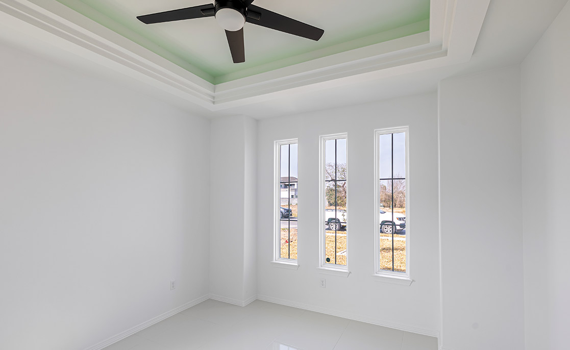 A spacious white room with a ceiling fan and windows, highlighting the importance of quality in custom home construction.