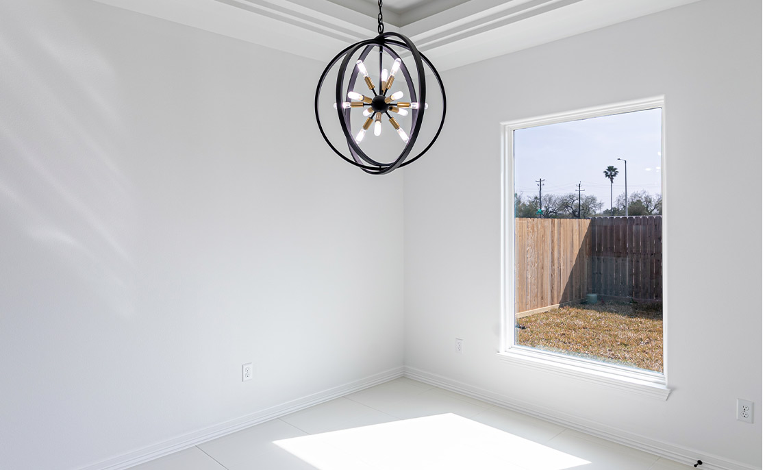 Villanueva Construction: A spacious white room adorned with a grand chandelier hanging from the ceiling, adding sophistication to the space.