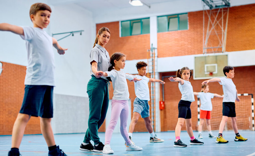 Group of school children exercising while physical education class with female coach. Copy space.